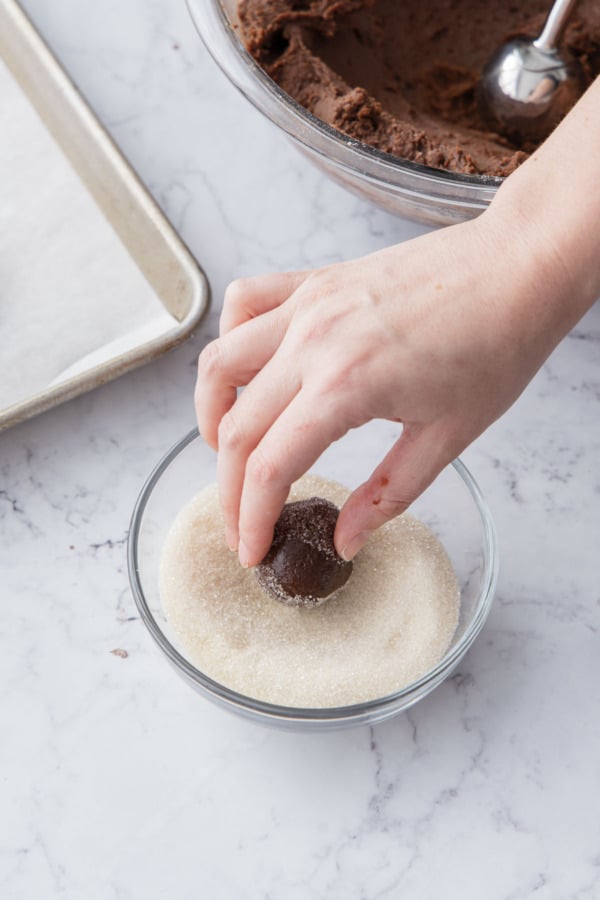 Rolling cookie dough balls in organic sugar for a crunchy, sparkly coating.