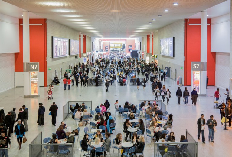 Crowds of people move through the atrium of a large conference centre
