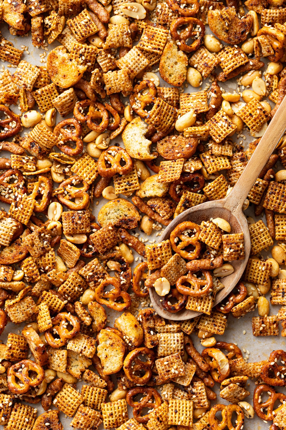 Sheet pan covered in homemade Sweet & Spicy Sesame Snack Mix with a wooden spoon.
