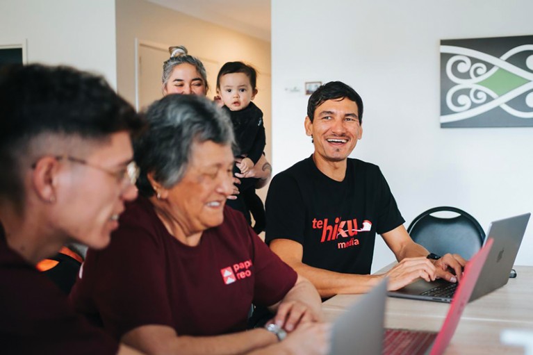 A member of Te Hiku Media working at laptops with members of the Māori community