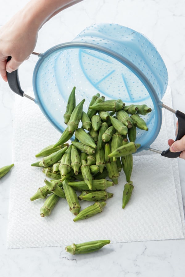 Dumping washed okra onto paper towels to dry.