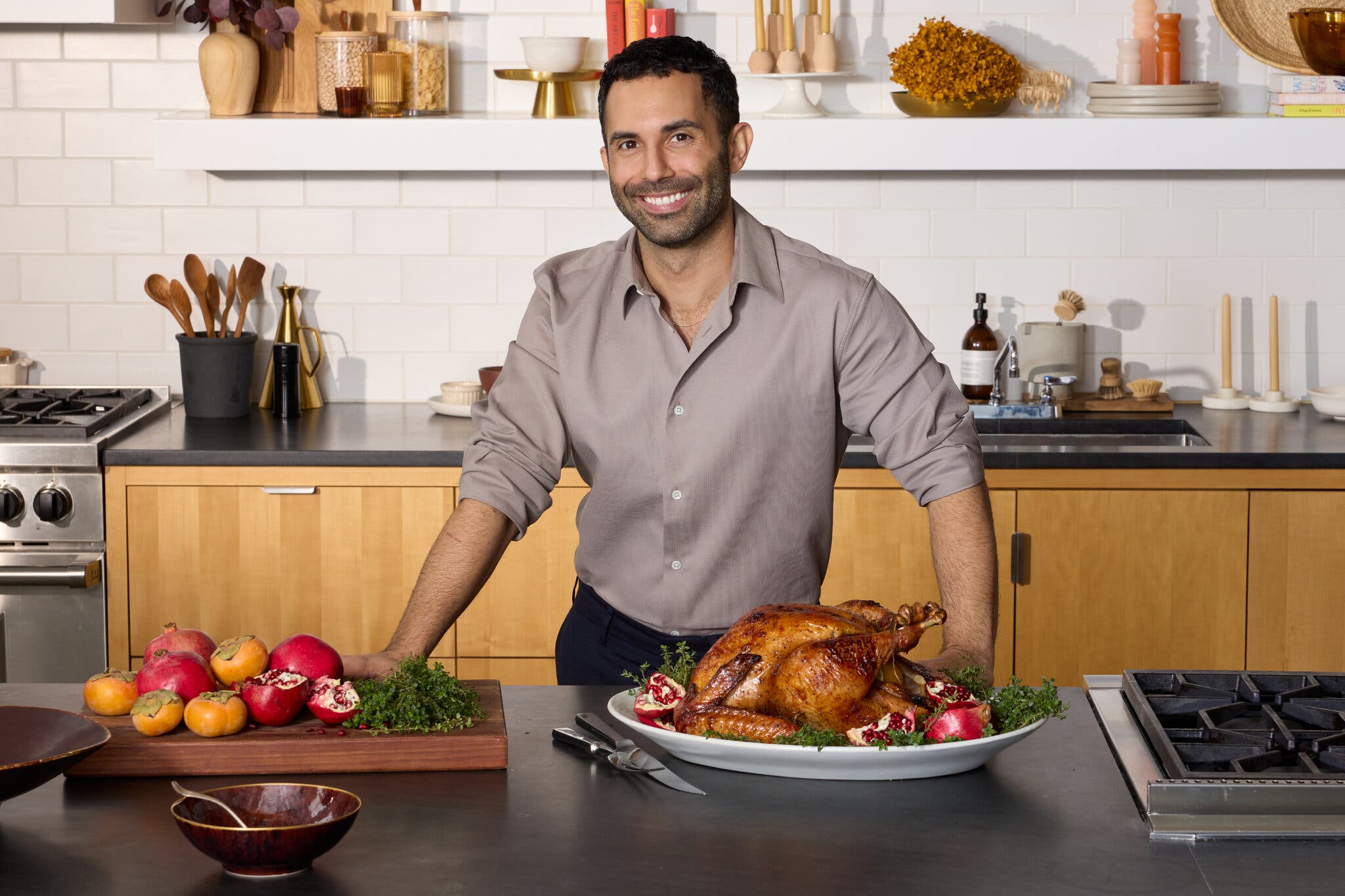 An image of a man at a kitchen counter with a turkey and some pomegranates.