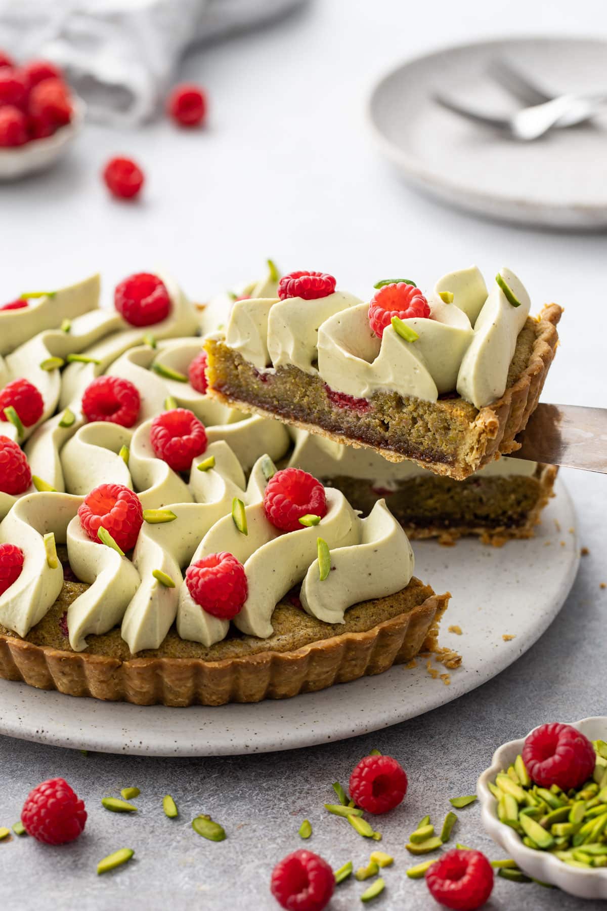 Slice of Raspberry Pistachio Frangipane Tart lifted to show the layers of pistachio frangipane and raspberry jam.