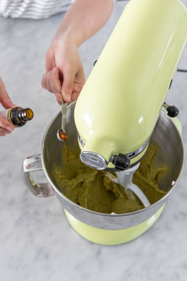 Adding pistachio extract to mixing bowl with pistachio frangipane mixture.